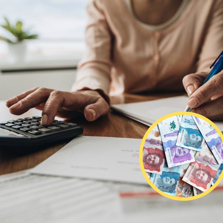 Mujer usando una calculadora, encima dinero colombiano (GettyImages)
