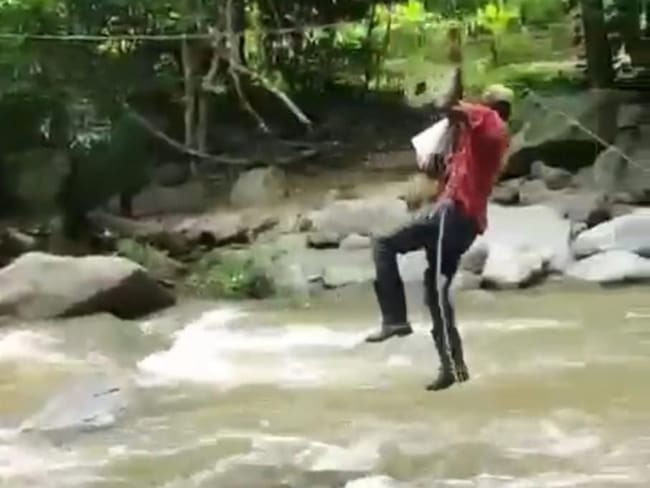 Hombre cruzando el río con un bebé/ Captura de pantalla video/ Erika López.