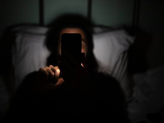 Persona mirando el celular en la oscuridad. Foto: Gettyimages.