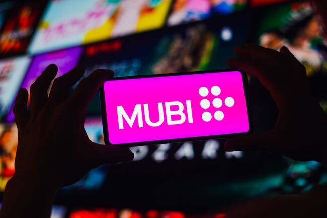 Persona sosteniendo un celular con el logo de Mubi en su pantalla